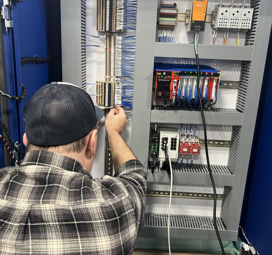 Technician landing field wires on terminal strips in a safety PLC panel